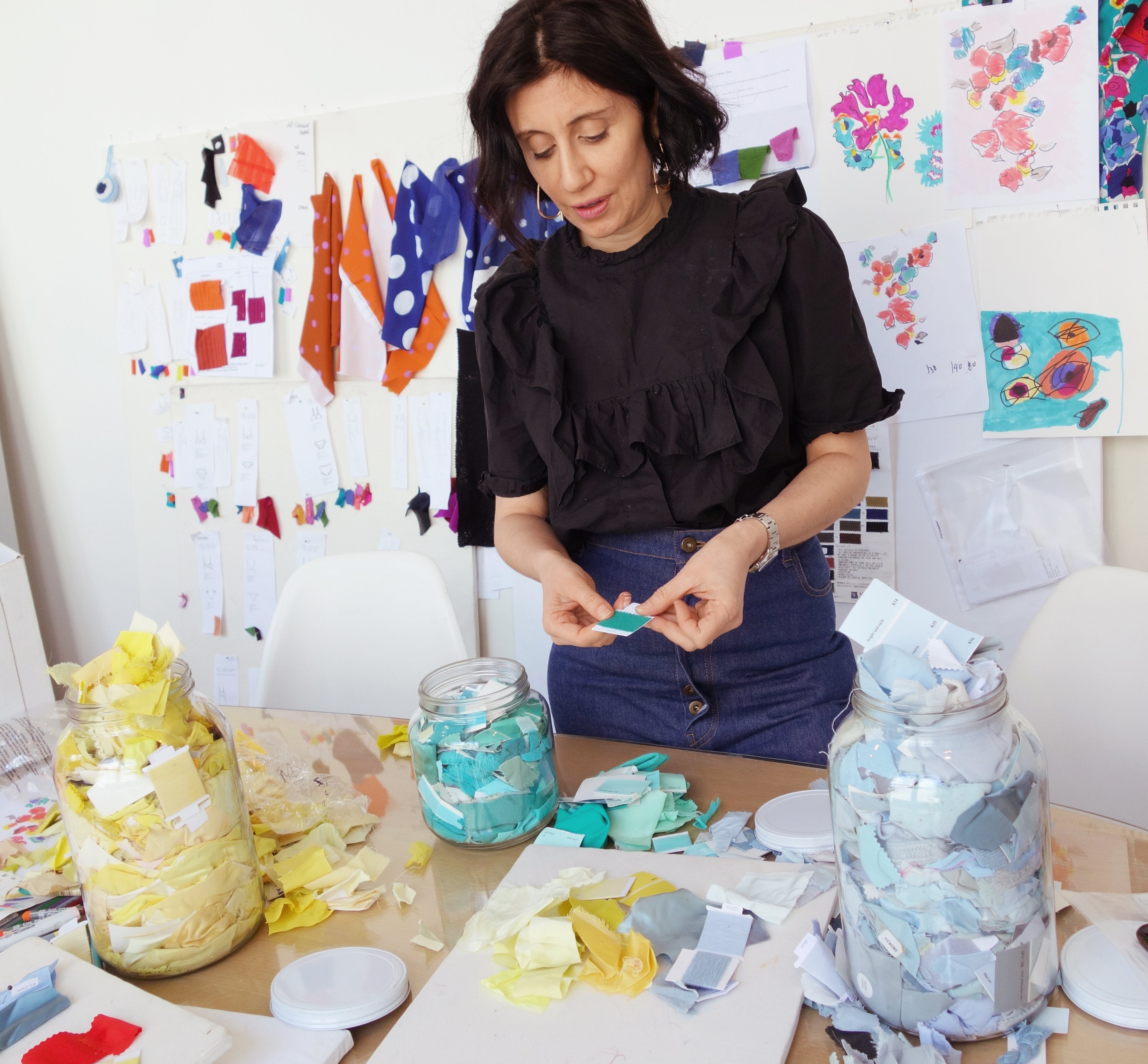 Woman standing at table working with swatches of colorful fabric